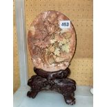 FINELY CARVED SOAPSTONE PLAQUE OF BIRD AMONGST FLOWERS ON CARVED SIMULATED ROOT WOOD STAND