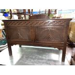 OAK CARVED TWO PANEL COFFER RAISED ON STILE FEET