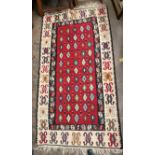 GEOMETRIC PATTEREND FRINGED CARPET ON RED GROUND 197CM X 105CM