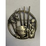 WHITE METAL BROOCH DEPICTING A MAN PLAYING A DRUM AMONGST PALM TREES