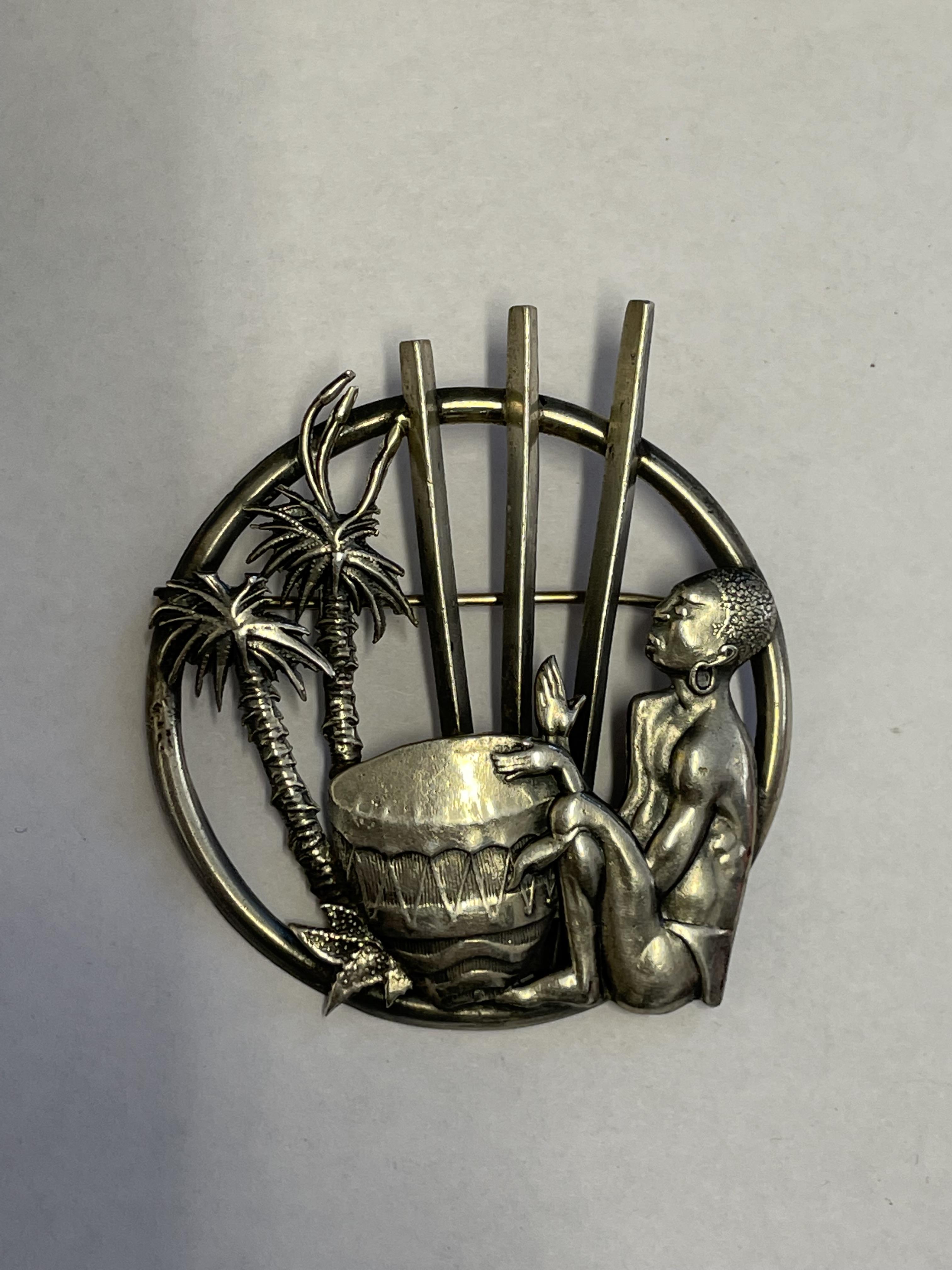 WHITE METAL BROOCH DEPICTING A MAN PLAYING A DRUM AMONGST PALM TREES - Image 2 of 4