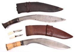 A kukri, with one piece bone hilt, in its leather covered sheath with two companion knives with bone