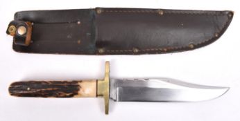 A Bowie knife, clipped back blade 5¾", with partly scalloped back edge, the hilt with brass