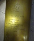 An engraved brass 25pdr cartridge case; a detonator from 25pd cartridge case, inert; a leather