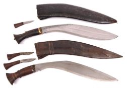 A kukri, with plain wood hilt, in its leather covered sheath with two companion knives; and