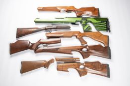 5 modern air rifle stocks, four being of wood and one of green and black laminate, all have been
