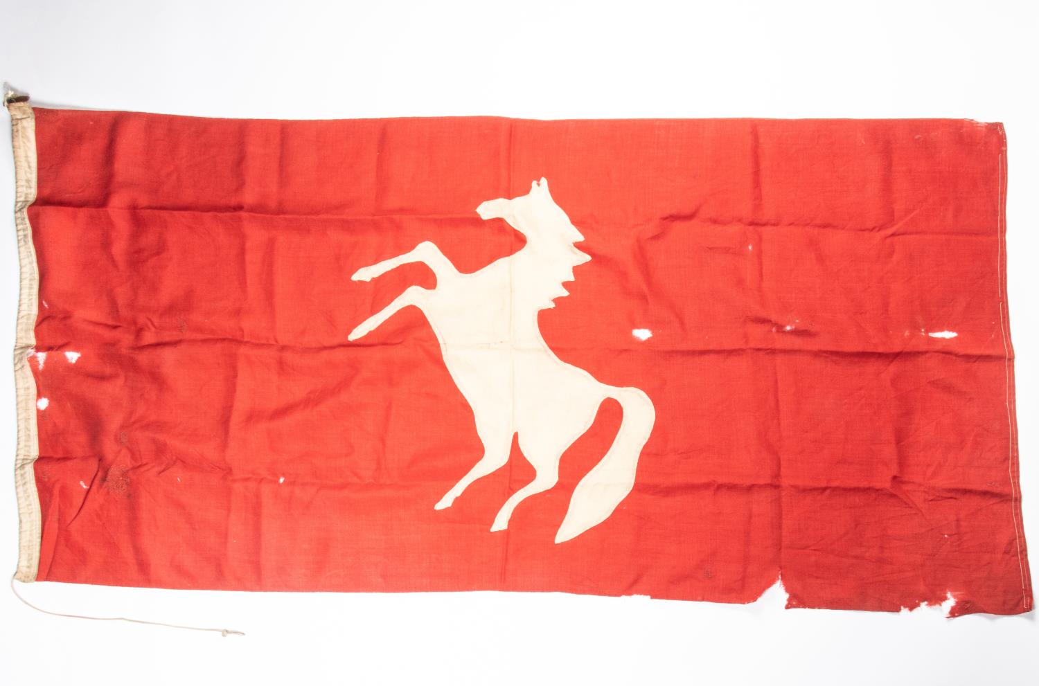 A WWI military flag, 68" x 33", red cloth with white prancing horse applied, possibly a divisional