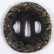 A Japanese blackened cast brass tsuba, deeply embossed around the rim with entwined dragons. GC £