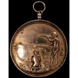 A 9 ct gold shooting award, obverse shooting left with clay pigeon operative kneeling at his feet,