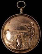 A 9 ct gold shooting award, obverse shooting left with clay pigeon operative kneeling at his feet,