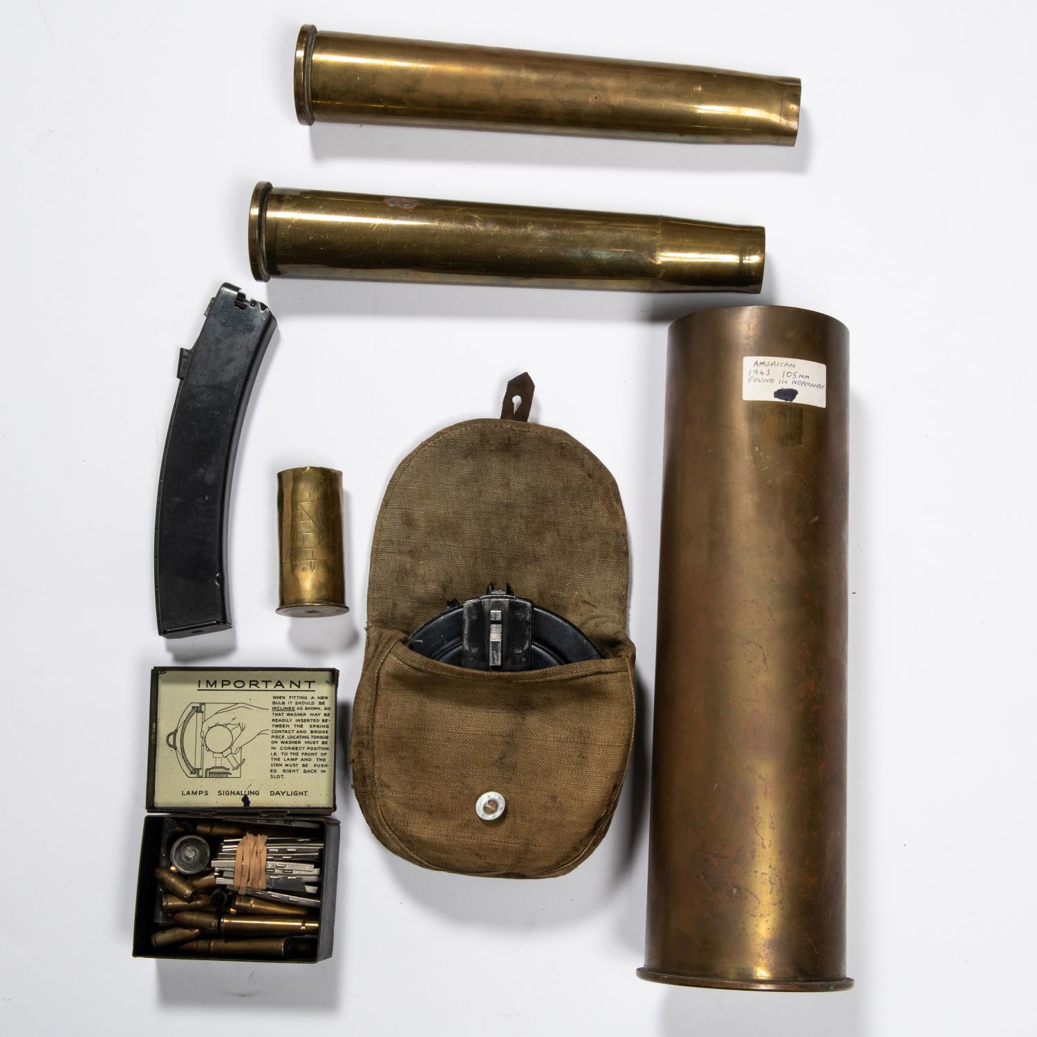 A 105mm WWII brass shell case, dated 1943; 2 40mm AA shell cases; a PPSH drum magazine; also a small