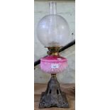 A pink glass and brass oil lamp with cast metal base.