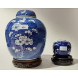 Two Chinese pottery ginger jars on carved wood bases, one without lid.