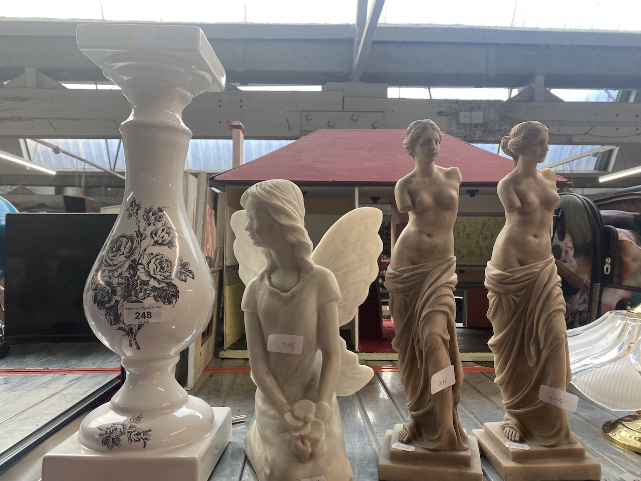 A pair of classical figures, a fairy statue and a jardiniere stand