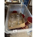 A box containing red glass vases and a box of glass desert dishes