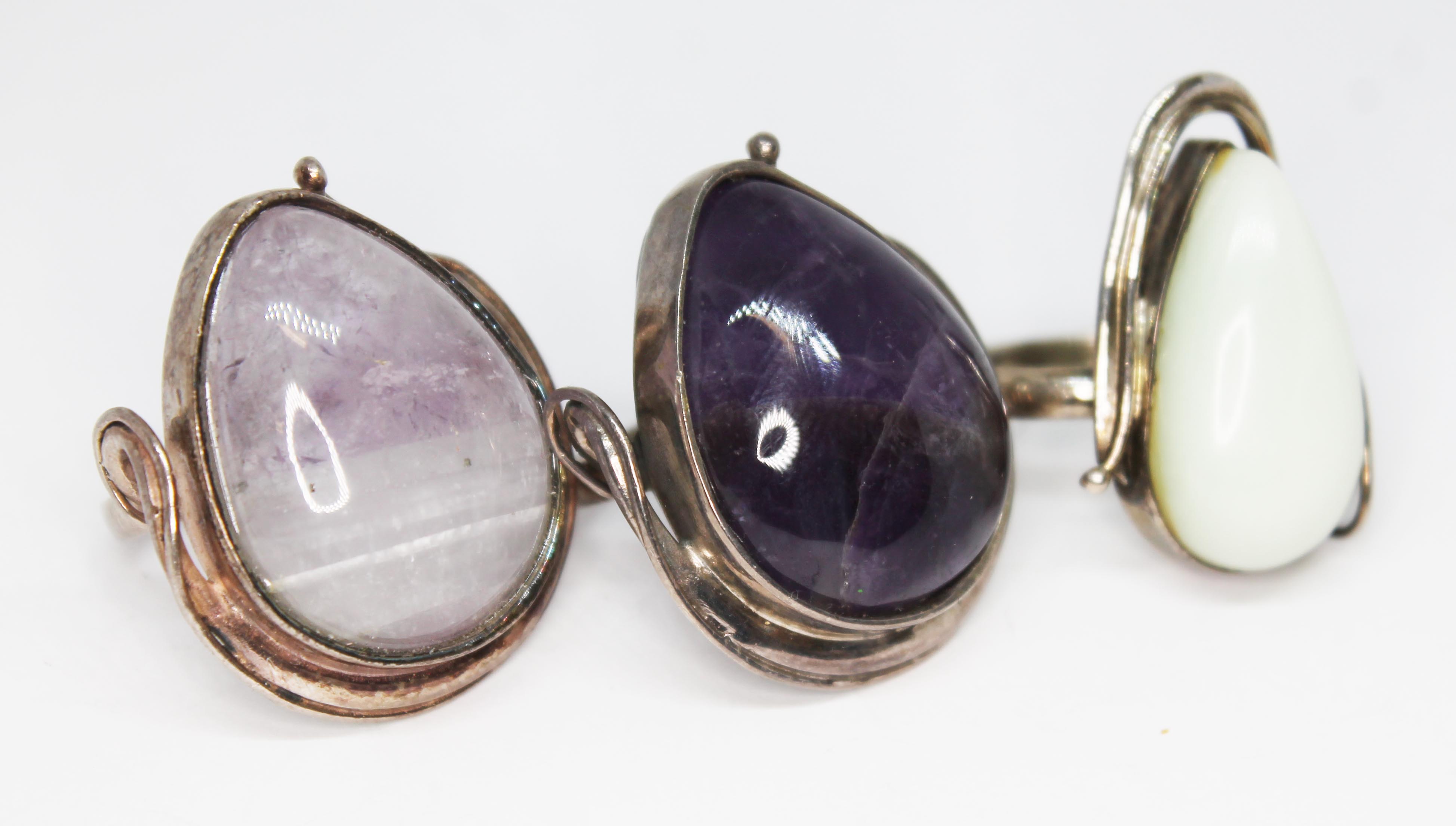 Three Art Nouveau style cabochon rings, two set with fluorite and the other a pale cream stone,