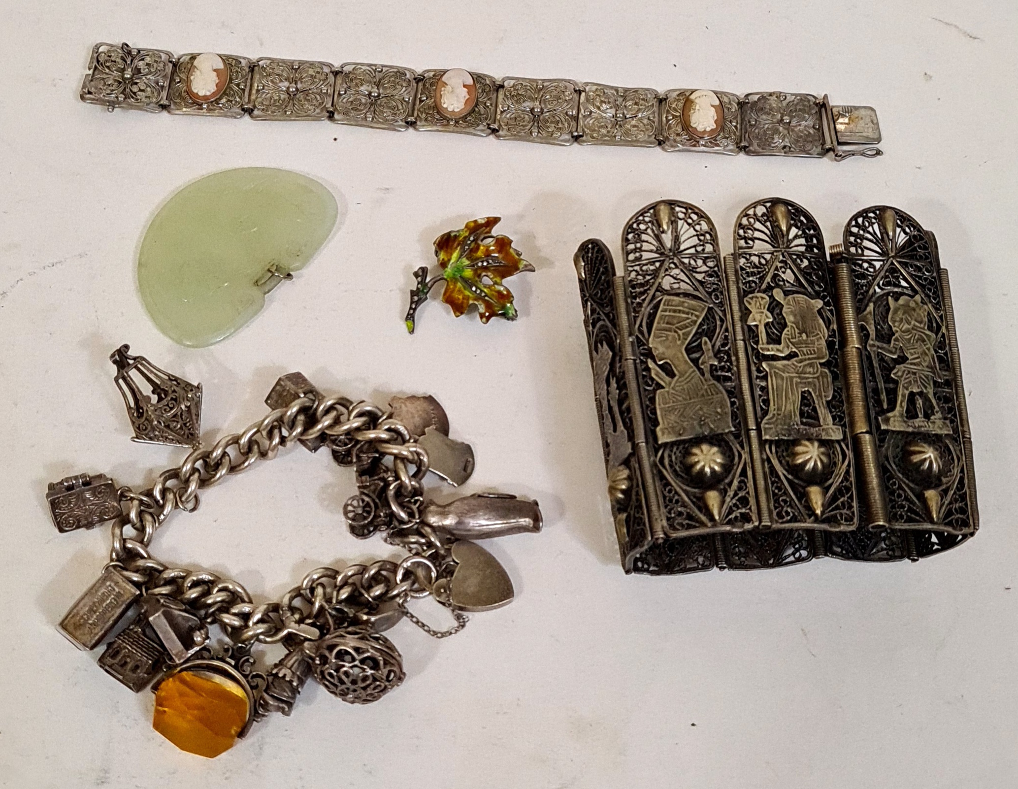 A antique silver bracelet with various charms, some marked silver, a German silver bracelet with