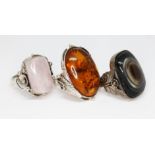 Three Art Nouveau style cabochon rings, one set with rose quartz, another with amber and one with an