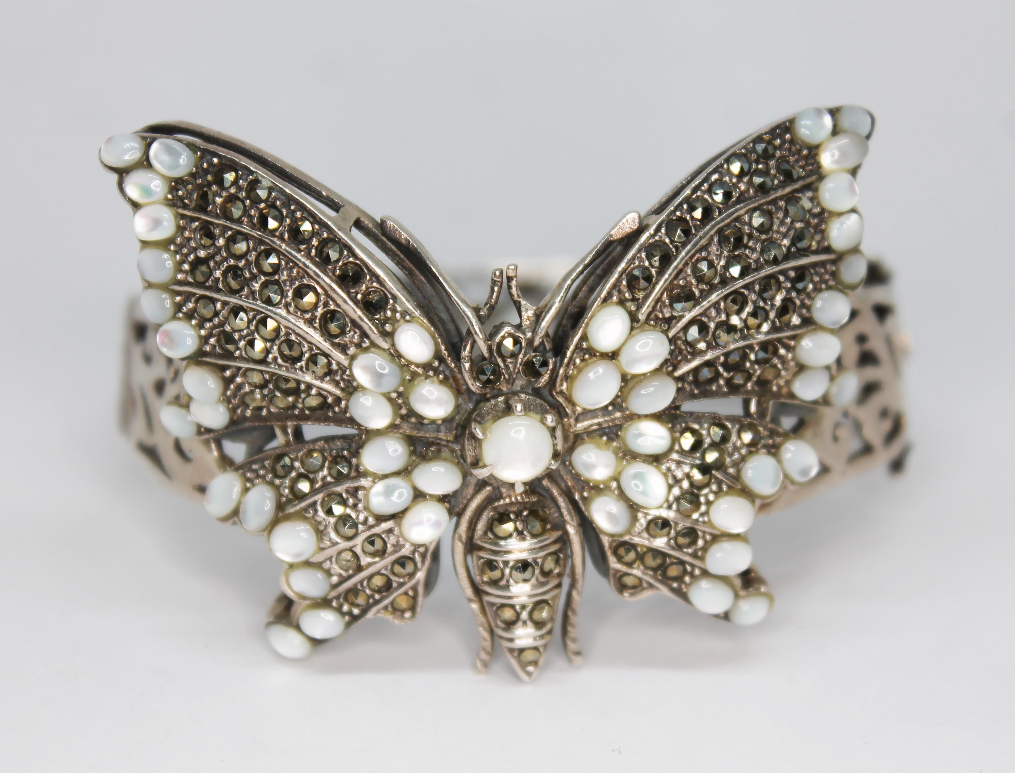 A white metal butterfly bangle set with marcasite and moonstones, unmarked, gross wt. 45.76g,