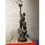 A metal figural table lamp in shape of a woman holding flame in hand.