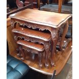 A carved mahogany nest of tables with cabriole legs.