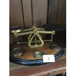 A small wood and brass set of weighing scales with weights.