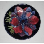 A Moorcroft circular pin dish with red/mauve anemone design on blue ground diameter 4.5 inches