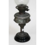 An antique oil lamp with lion heads in relief, with funnel, height including funnel approx 60cm.