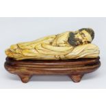 A carved Chinese ivory deity, circa 1900, on carved wooden base, length 14cm.
