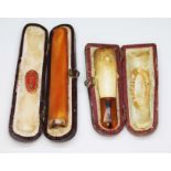 A yellow metal mounted butterscotch amber cheroot holder and another, both cased.