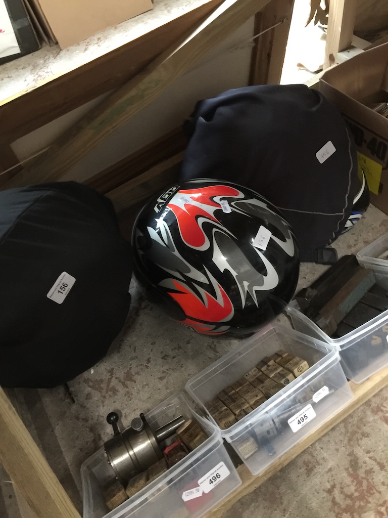A group of three motorcycle crash helmets and a box of electrical sockets.