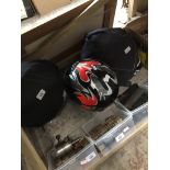 A group of three motorcycle crash helmets and a box of electrical sockets.