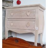 A chest of two drawers with heart shaped handles.