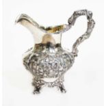 A Victorian silver jug, repousee decoration with flowers, gilt interior, scroll feet and cast figure
