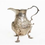 A George II silver cream jug, of baluster form, embossed and chased with floral bouquets, scroll