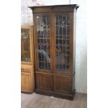 An Edwardian Arts & Crafts oak and leaded glass bookcase, width 102cm, depth 34cm & height 198cm.