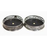 A pair of George III silver wine coasters of round form, piereced rail, mahogany base inlaid with