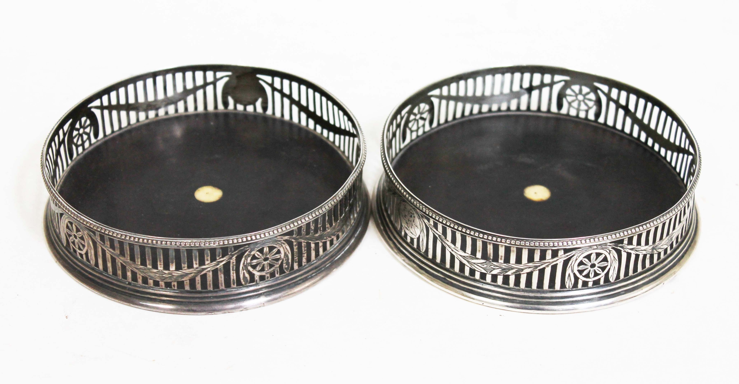 A pair of George III silver wine coasters of round form, piereced rail, mahogany base inlaid with
