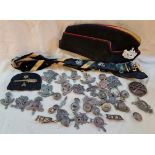 A box of assorted militaria cap badges, naval belt and cap with Egypt badge.