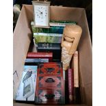 A box of misc including books, small plated photo frames, a blood pressure monitor, and a clock