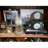 An old black slate mantel clock, a German Kundo brass and enamel face clock under glass dome, an