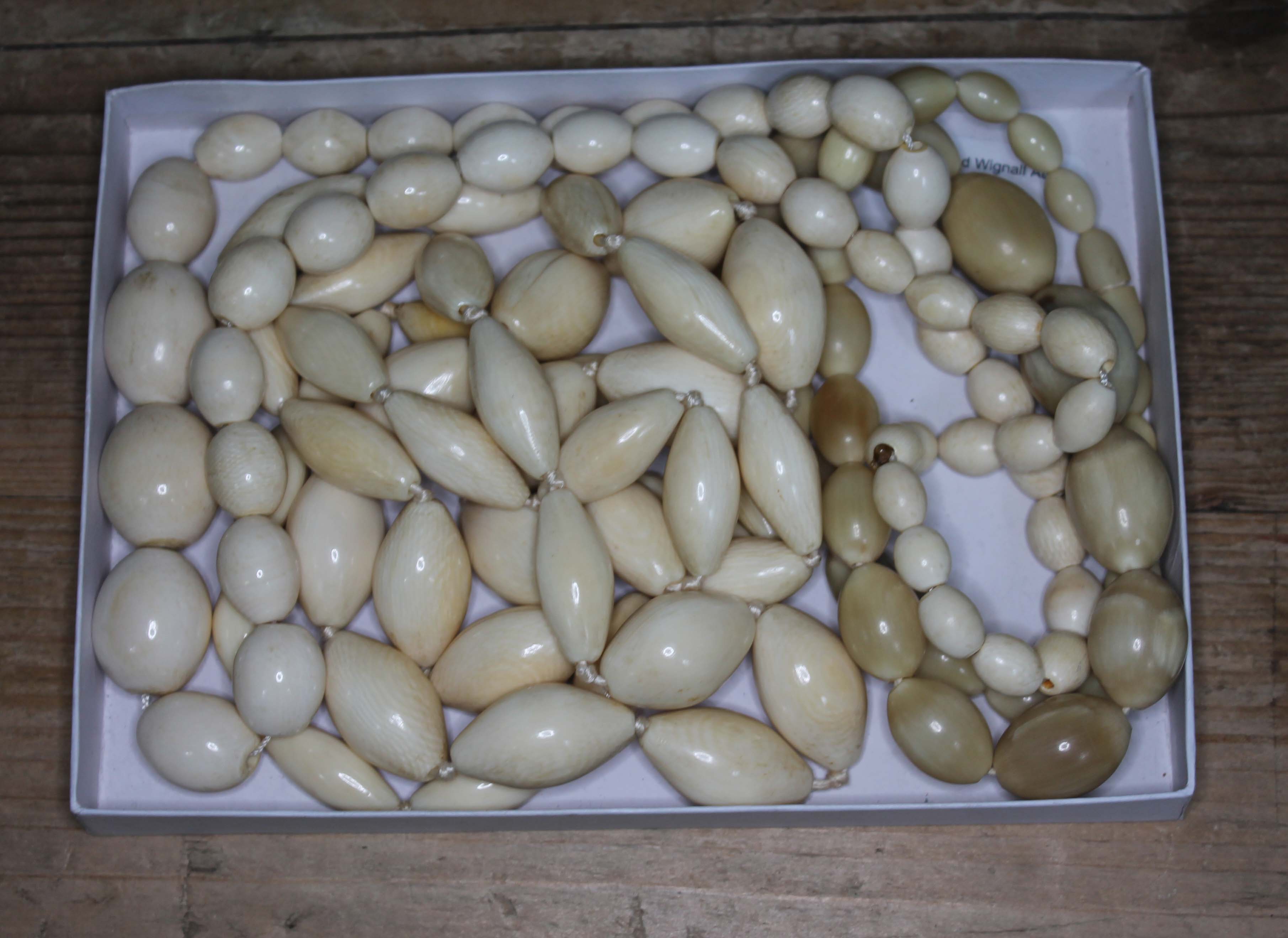 A tray of assorted beads comprising ivory, bone and horn, early 20th century.