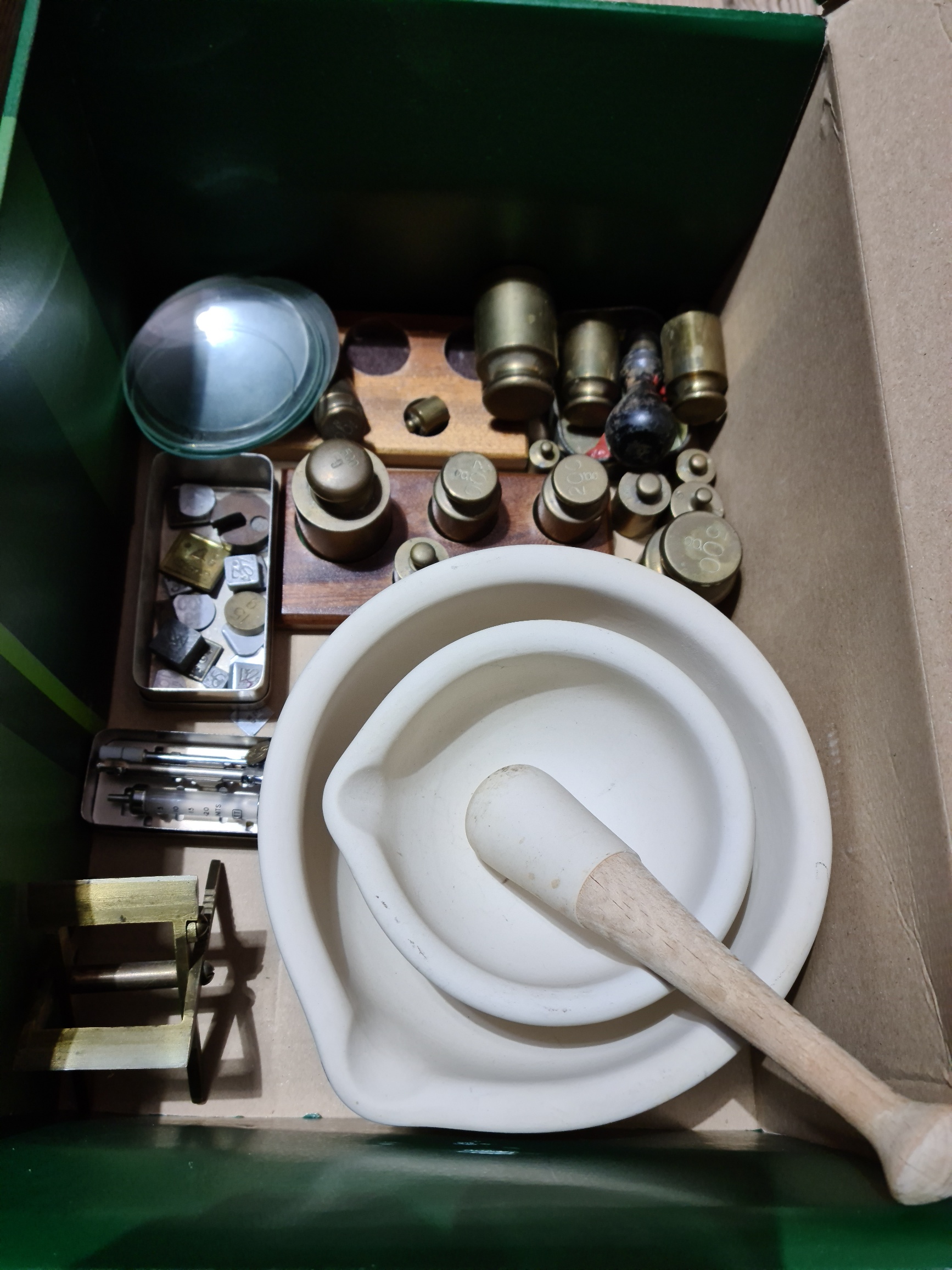 A box of assorted pharmaceutical items comprising weights, pestle and mortar etc.