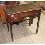 A George III oak lowboy with shaped frieze and three drawers, standing on squared legs, height 71cm,