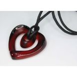 A Lalique red heart shaped pendant on black cord, signed. Condition - good, general wear only.