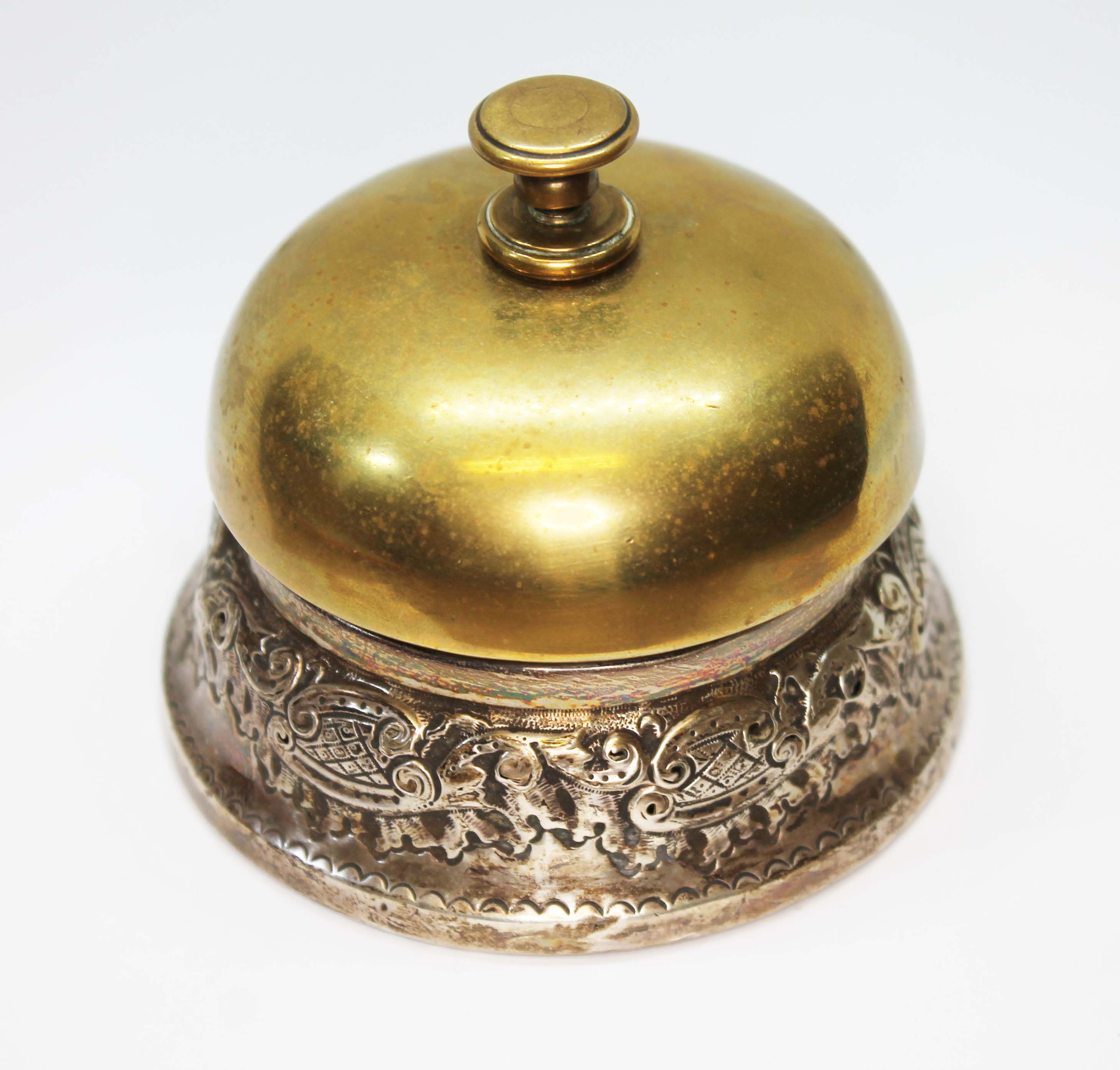 A white metal mounted brass desk bell, unmarked, diameter 8cm. Condition - various worn through