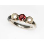A contemporary white metal ring set with two cultured pearls and a round cut garnet, indistinctly