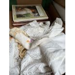 A box of lace and linen and related books.