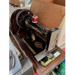 A hand-cranked Singer sewing machine in wooden case.