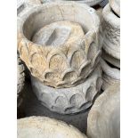 A pair of ornate concrete garden planters on pedestal bases.